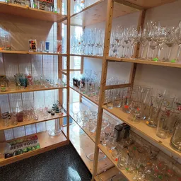 Glazen kasten vol met drinkglazen, wijnglazen en ander glaswerk uitgestald in de kringloopwinkel