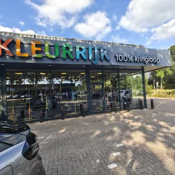 Gekleurde gevel van kringloopwinkel Kleurrijk met 100% kringloop-tekst, grote glasdeuren en naam duidelijk zichtbaar