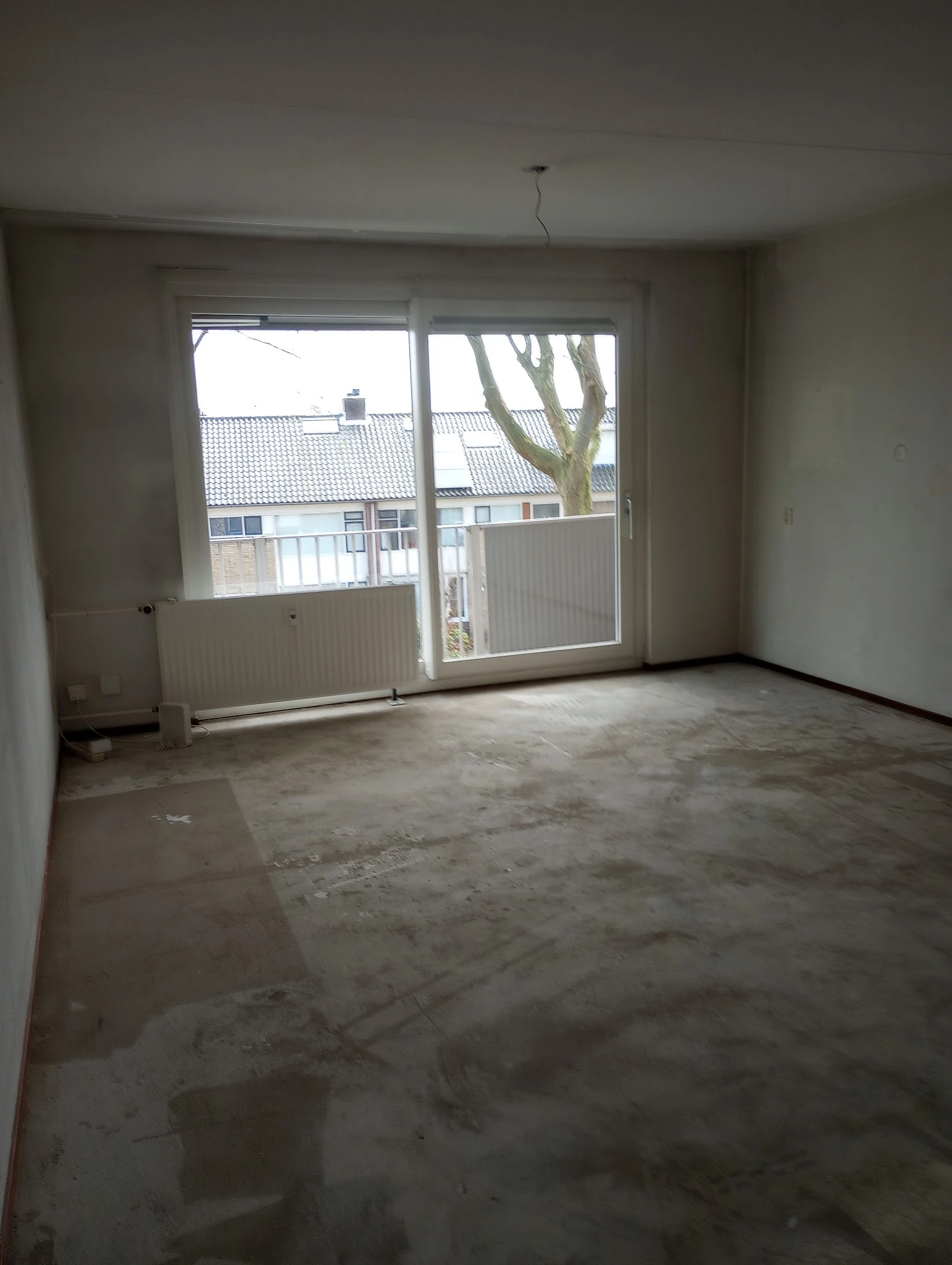 Leeg winkelinterieur met betonvloer, radiator en openslaande deuren met uitzicht op straat