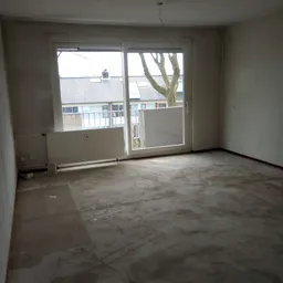 Leeg winkelinterieur met betonvloer, radiator en openslaande deuren met uitzicht op straat