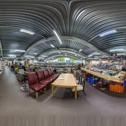 Overzicht van de winkelvloer met meubelstukken, huishoudapparatuur en diverse spullen onder een golfplaten plafond met LED-ve