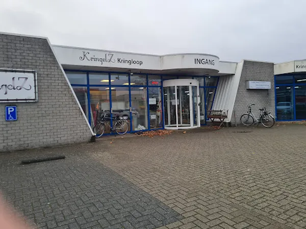 Gevel van kringloopwinkel KringelZ met blauwe kozijnen, ingang en enkele fietsen ernaast
