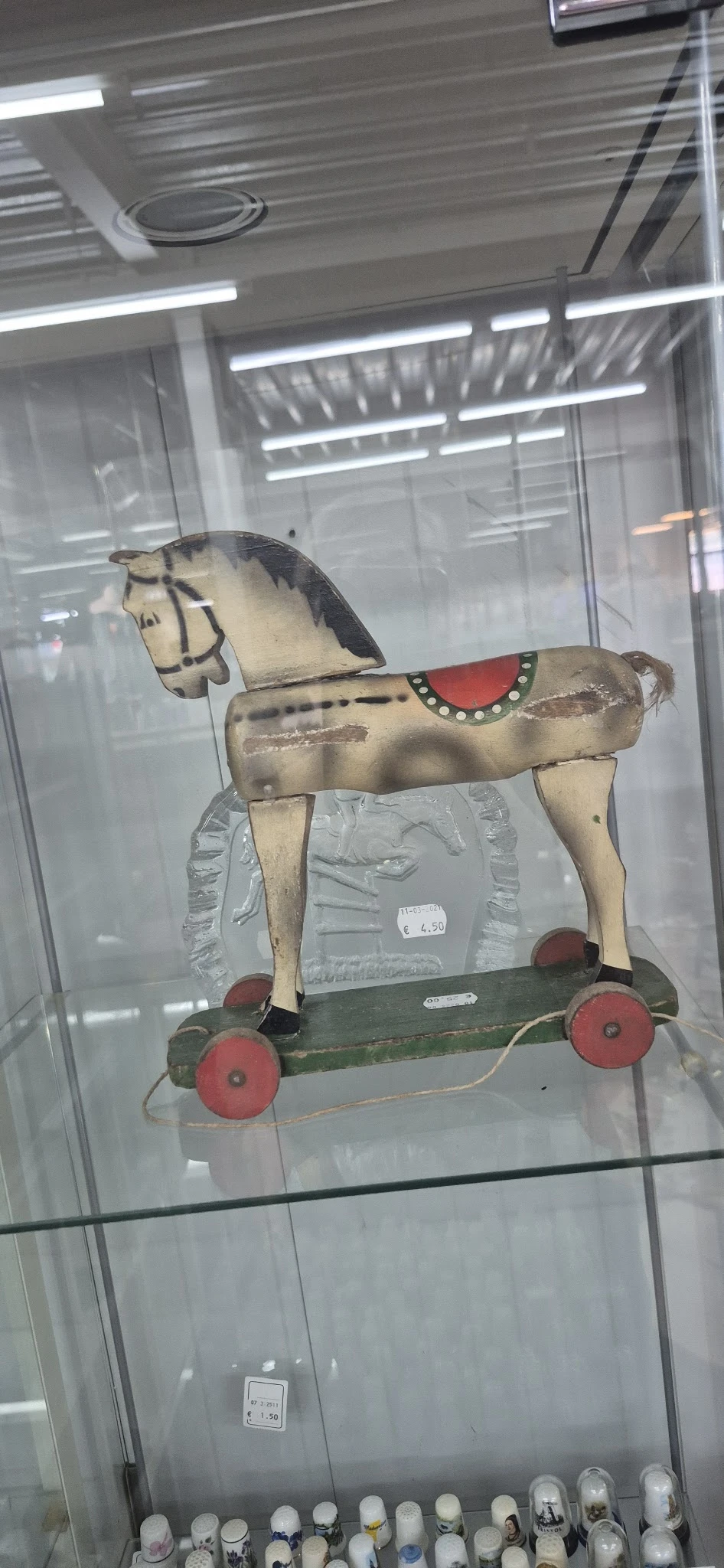 Antiek houten speelgoedpaard op wielen met beschildering en rood zadel
