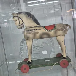 Antiek houten speelgoedpaard op wielen met beschildering en rood zadel