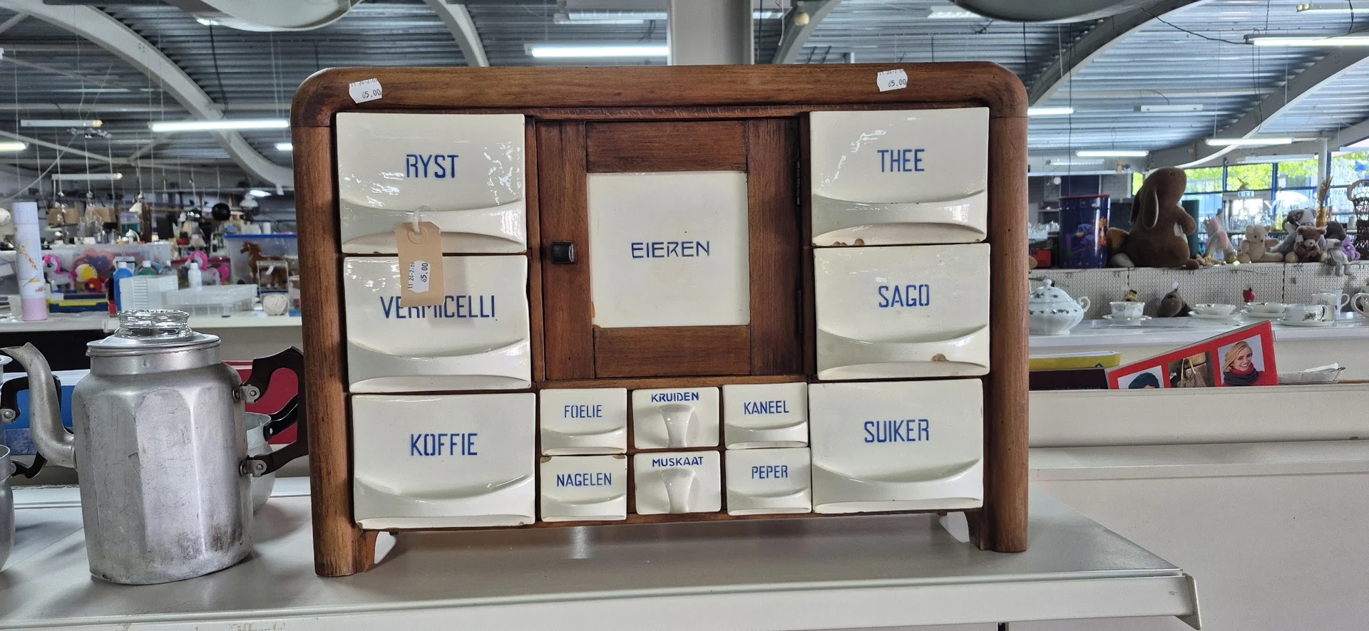 Houten kastje met emaille dozen voor koffie, thee, suiker en andere voorraden in een kringloopwinkel