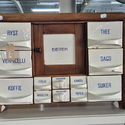 Houten kastje met emaille dozen voor koffie, thee, suiker en andere voorraden in een kringloopwinkel