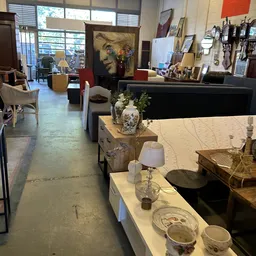 Winkelvloer van kringloopwinkel met toonbanken, lampen, serviesgoed en decoratieartikelen uitgestald