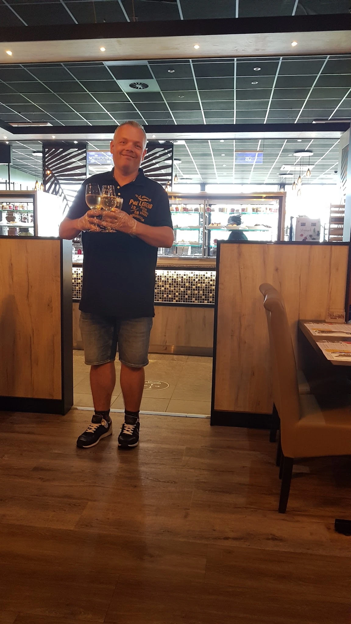 Man met glas wijn in een lunchroom of winkelhoek met houten wanden
