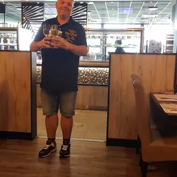 Man met glas wijn in een lunchroom of winkelhoek met houten wanden