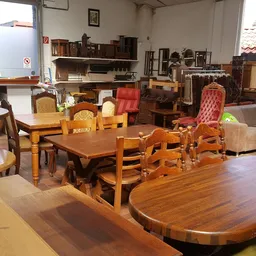Interieur van kringloopwinkel met houten meubels, tafels, stoelen en kasten uitgestald