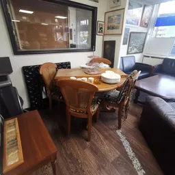 Woonkamer interieur met houten eettafel, rieten stoelen en donkerblauwe bank