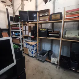 Houten stellingen met elektronische apparatuur zoals beeldschermen, versterkers, speakers en andere audio-apparatuur