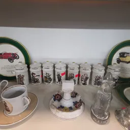Verzameling vintage serviesgoed met vintage auto-afbeeldingen, waaronder borden, bekers en decoratieve items