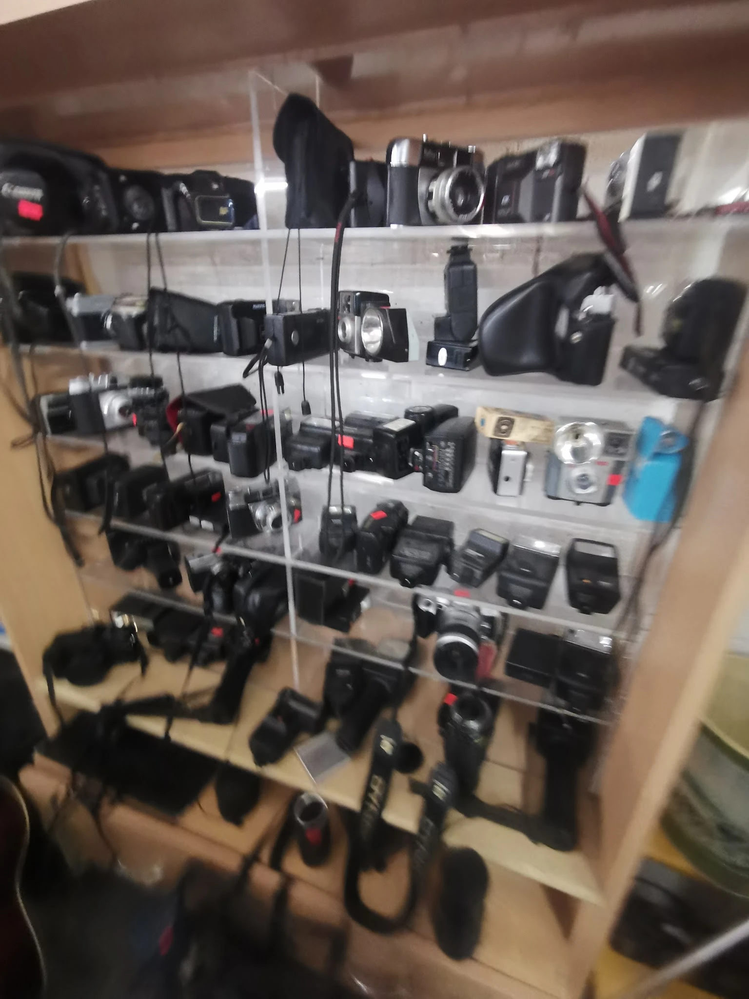 Vitrinekast met verzameling tweedehands camera's, flitsers en fotografische apparatuur