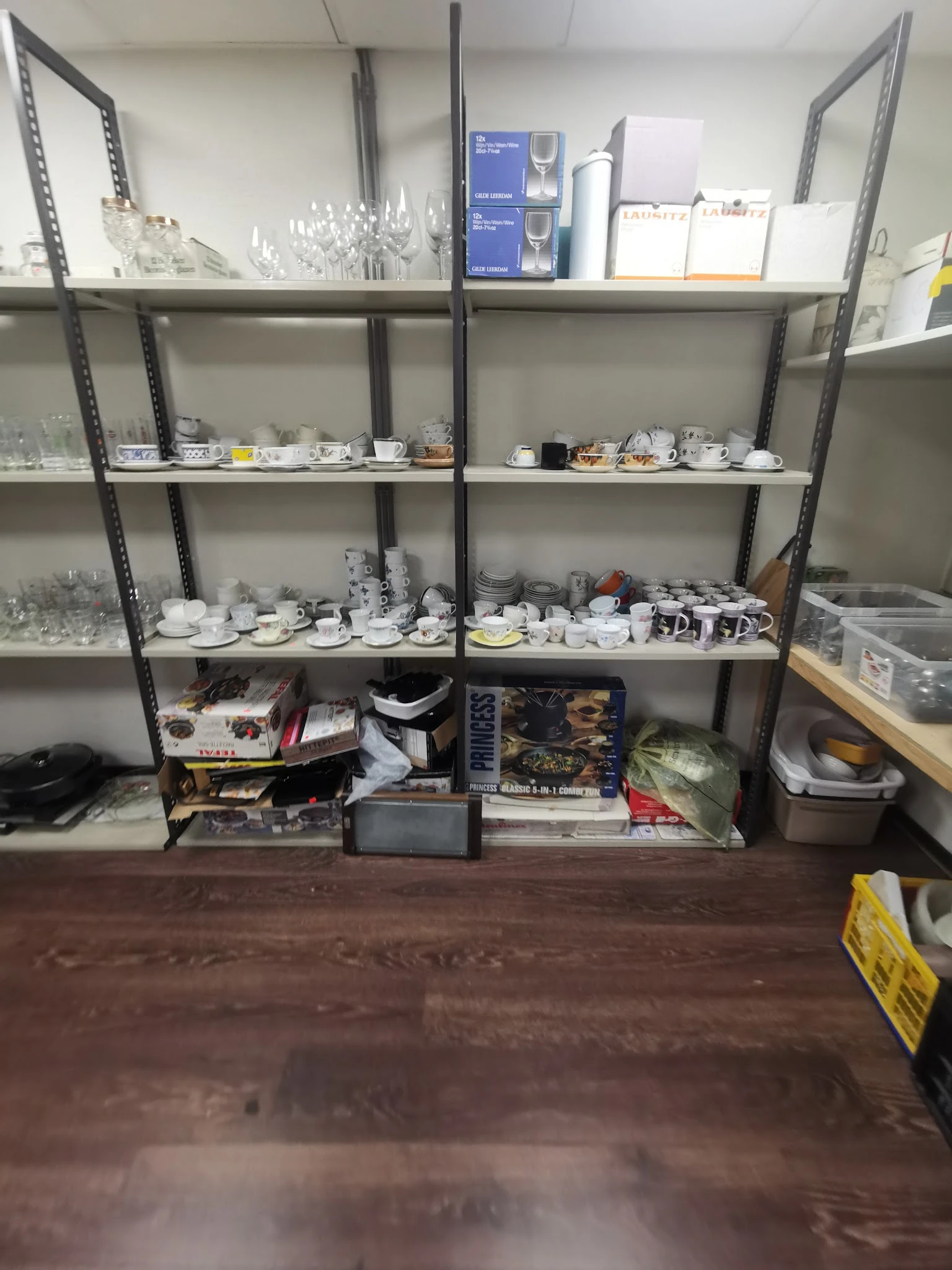 Stellingen met servies, borden en kopjes in een kringloopwinkel