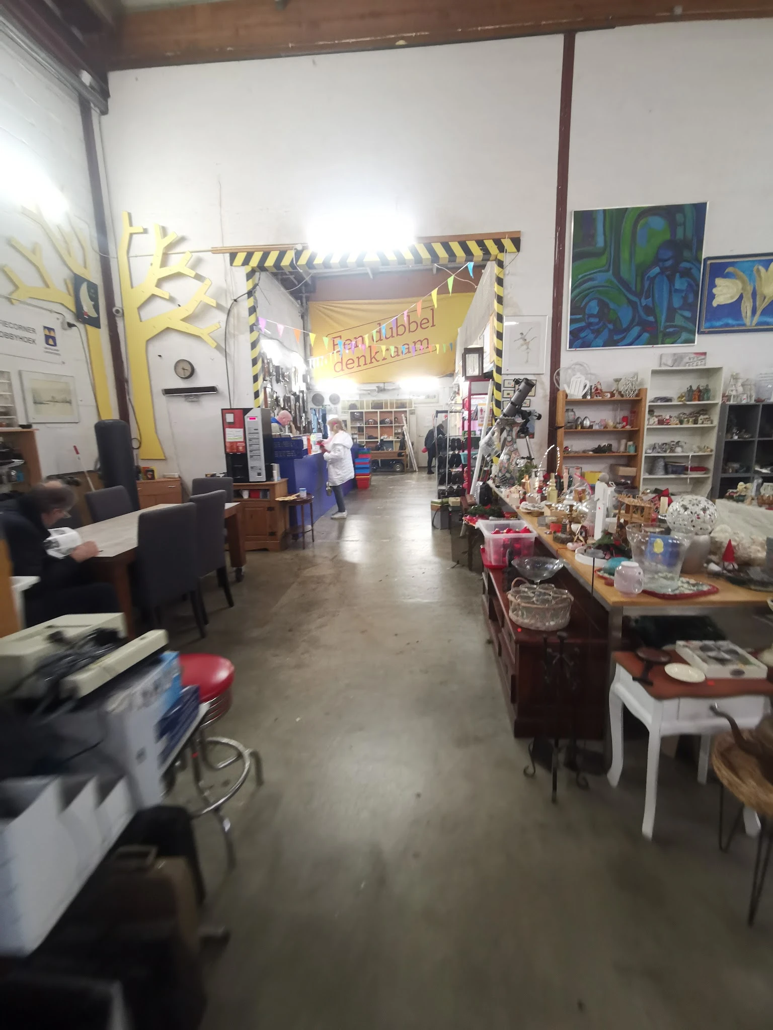 Overzicht van de winkelvloer met stellingen, tafels met spullen en decoraties langs de zijkanten
