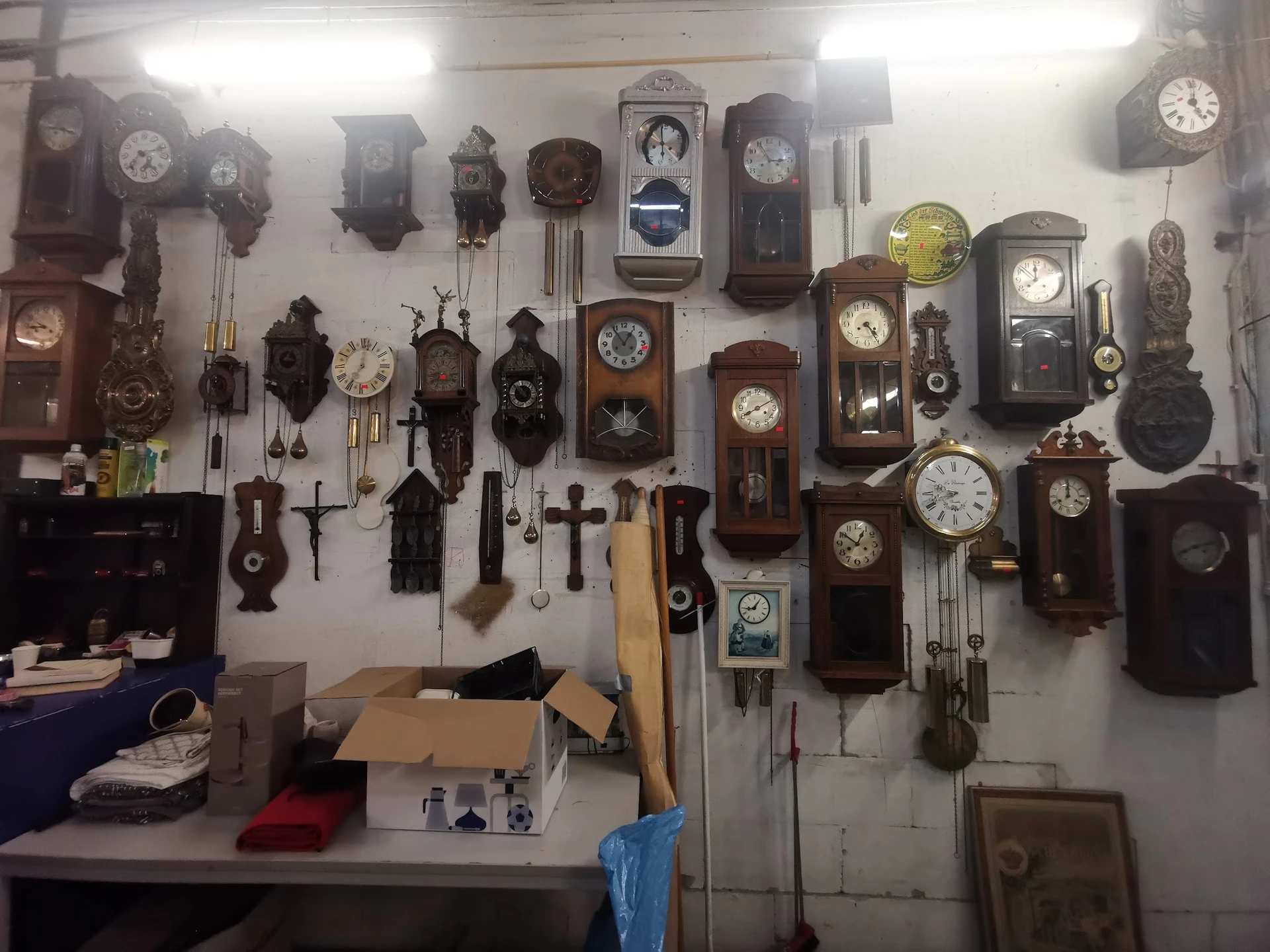 Muur vol met diverse antieke en vintage wandklokken in verschillende stijlen en formaten
