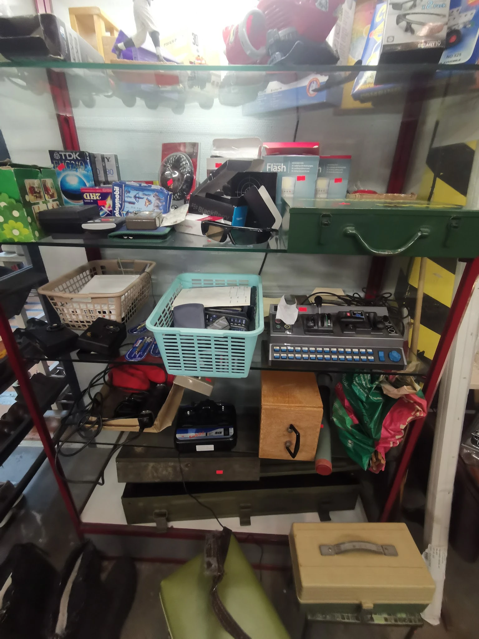 Stellingkast met verzameling elektronica, audio-apparatuur en vintage items zoals kassettebandjes en elektronische apparaten