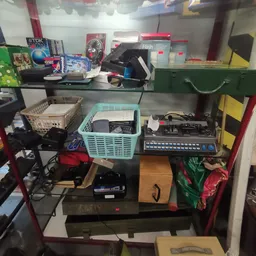 Stellingkast met verzameling elektronica, audio-apparatuur en vintage items zoals kassettebandjes en elektronische apparaten