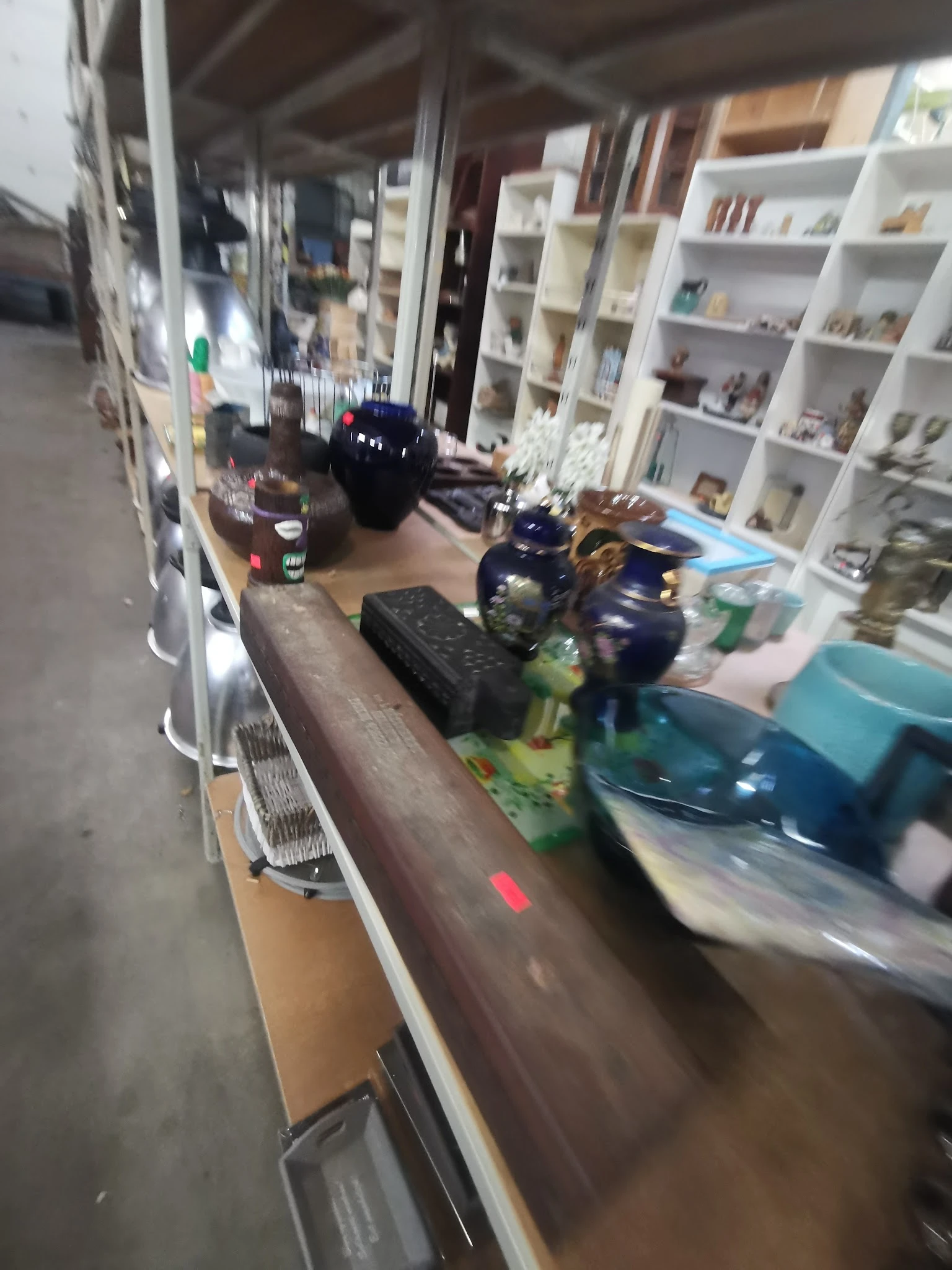 Diverse spullen op een plank: flesjes, een zwarte doos, speelgoedauto's en andere voorwerpen.