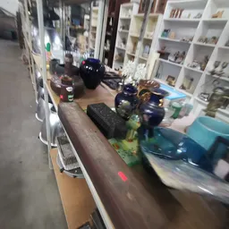 Diverse spullen op een plank: flesjes, een zwarte doos, speelgoedauto's en andere voorwerpen.