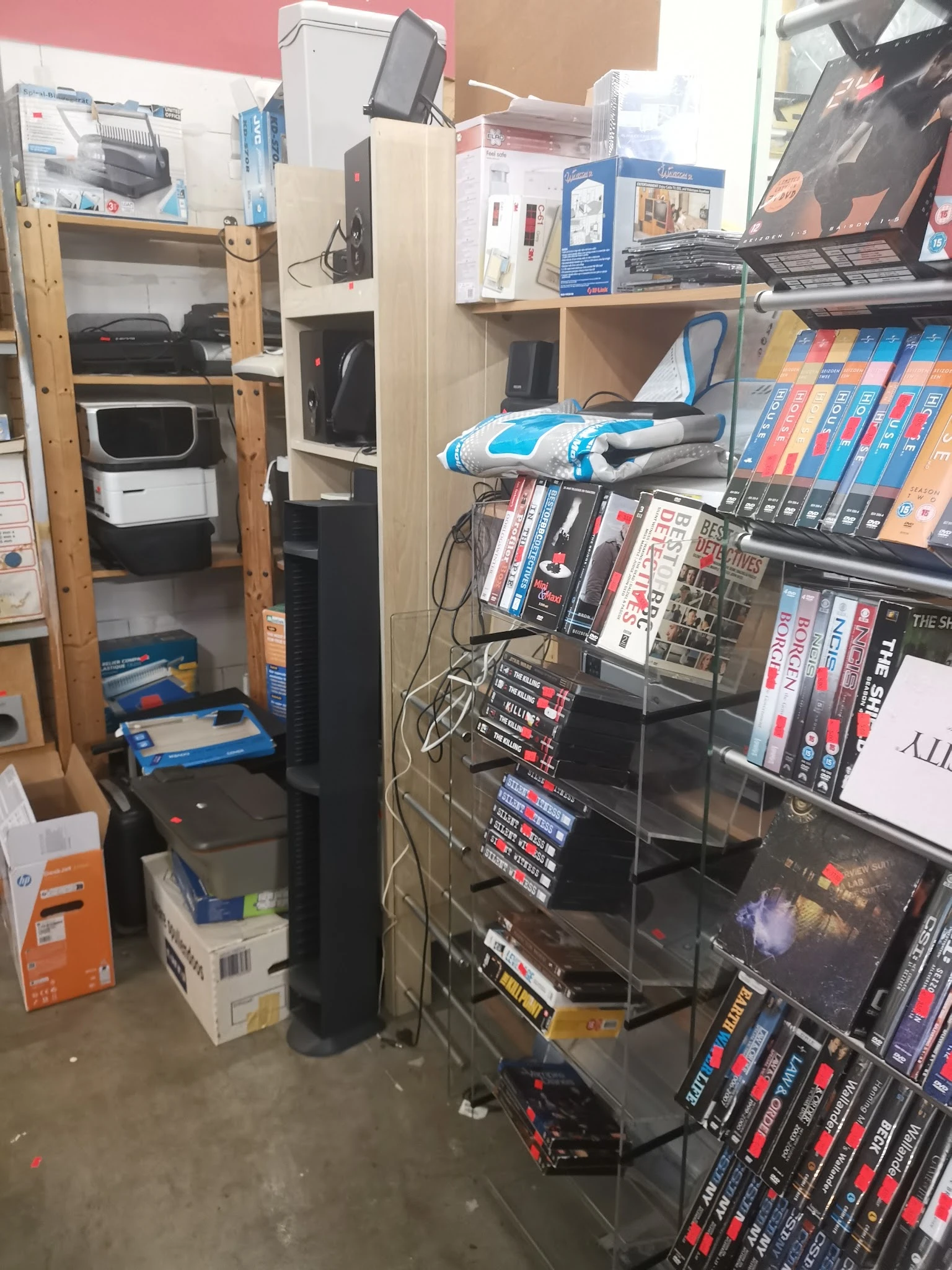 Rekken met dvd's, blu-rays en boeken in de winkel, met enkele dozen op de grond