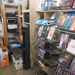 Rekken met dvd's, blu-rays en boeken in de winkel, met enkele dozen op de grond
