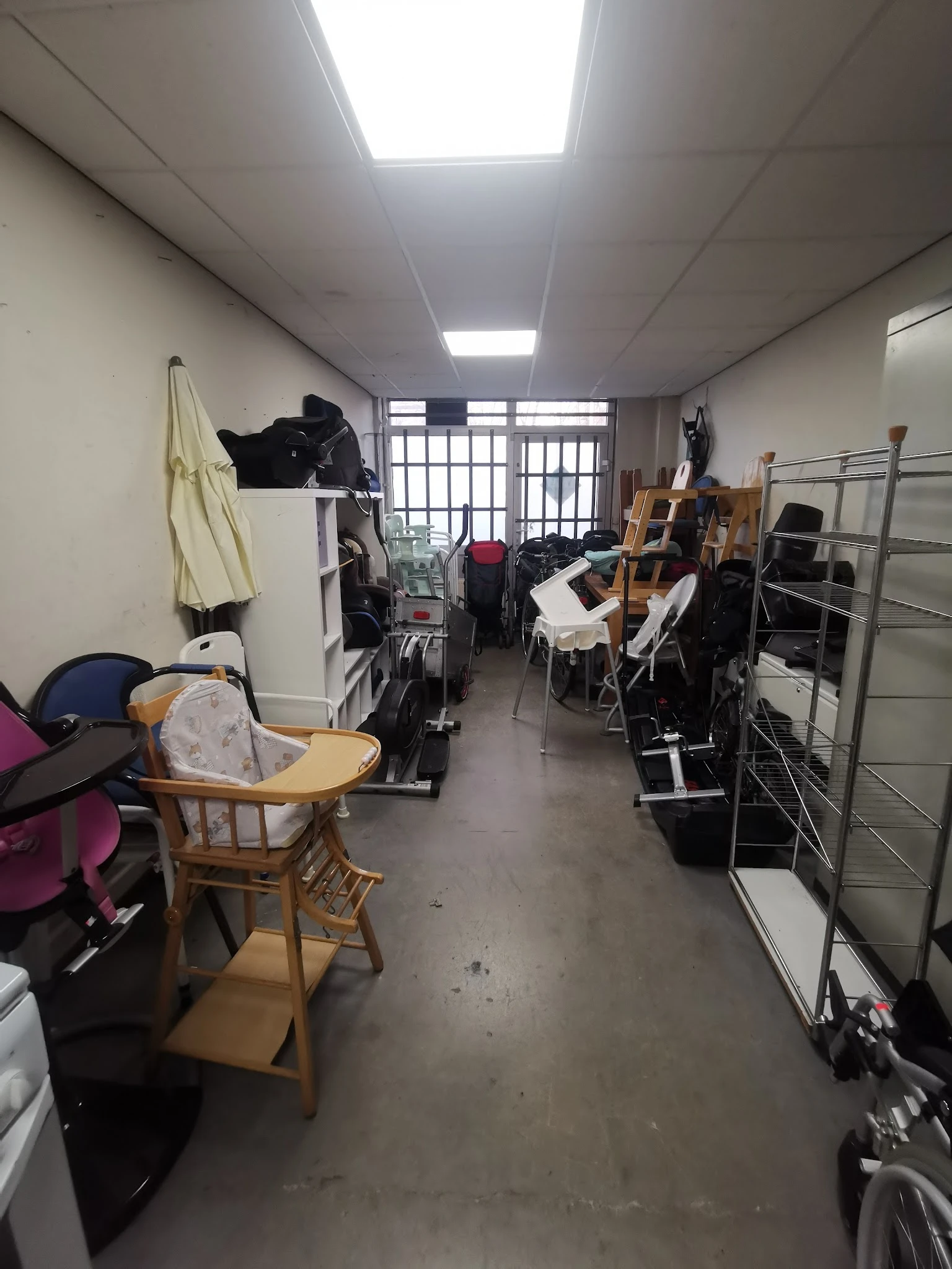 Rommelige opslagruimte of werkplaats met muziekinstrumenten, stoelen, kleding en diverse spullen