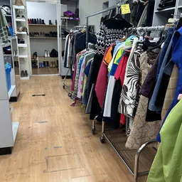 Rekken met tweedehands dameskleding in verschillende kleuren en patronen in de winkel