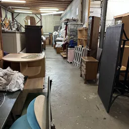 Winkelinterieur met diverse meubels en voorwerpen langs de zijkanten, betonnen vloer, daglicht van bovenaf