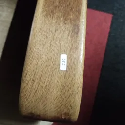 Close-up van een houten meubelstuk met een wit prijskaartje waarop '2.50' staat