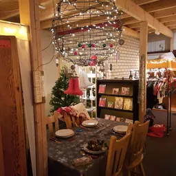 Winkelvloer met feestelijk gedecoreerde eettafel, kerstversiering en rekken met kleding en boeken