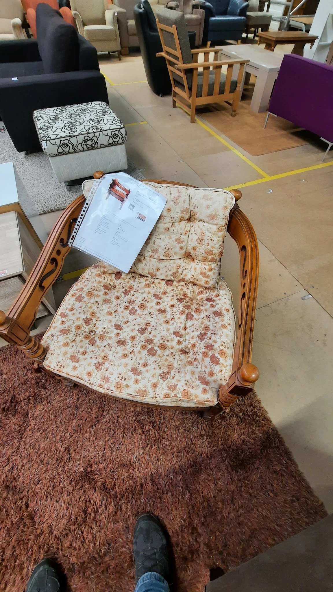 Houten fauteuil met beige/roze bloemenpatroon en een instructiepapier op de zitting