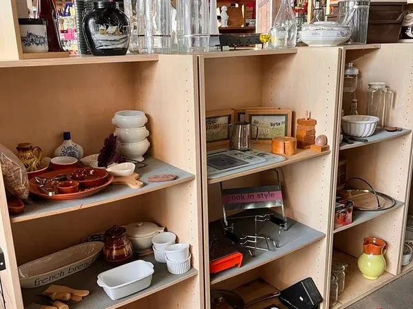 Open stellingen met huishoudartikelen zoals servies, bakvormen, glazen en decoratieve items