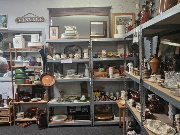 Stellingen met serviesgoed, huishoudelijke artikelen en vintage spullen in een kringloopwinkel