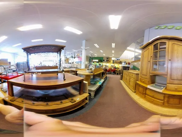 Ruim kringloopwinkelinterieur met houten meubels, vitrines en stellingen vol tweedehands spullen