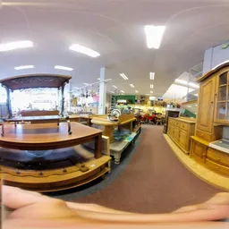 Ruim kringloopwinkelinterieur met houten meubels, vitrines en stellingen vol tweedehands spullen