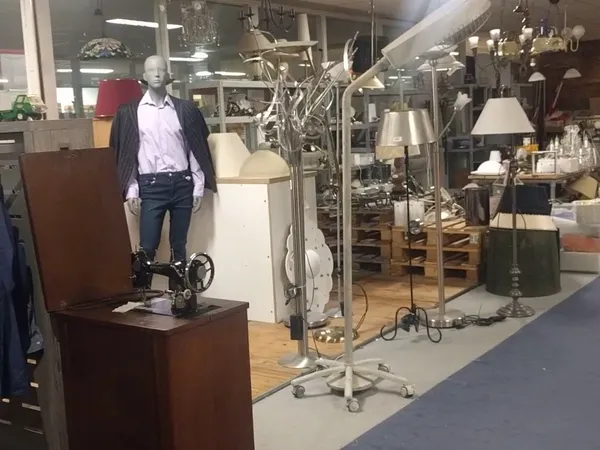 Winkelinterieur met mannequin in vrijetijdskleding, diverse lampen en meubels uitgestald