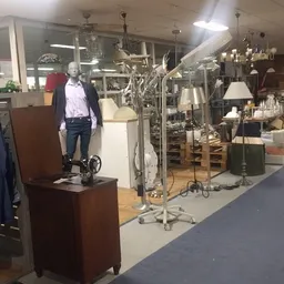 Winkelinterieur met mannequin in vrijetijdskleding, diverse lampen en meubels uitgestald