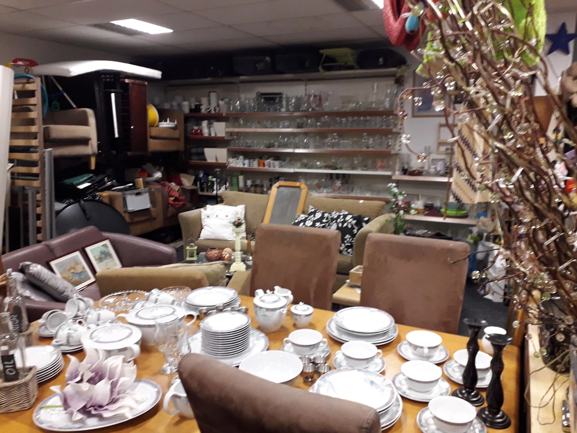 Eettafelset met servies en glazen, omgeven door huishoudelijke artikelen en meubels in de winkel