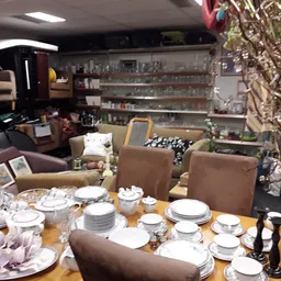 Eettafelset met servies en glazen, omgeven door huishoudelijke artikelen en meubels in de winkel
