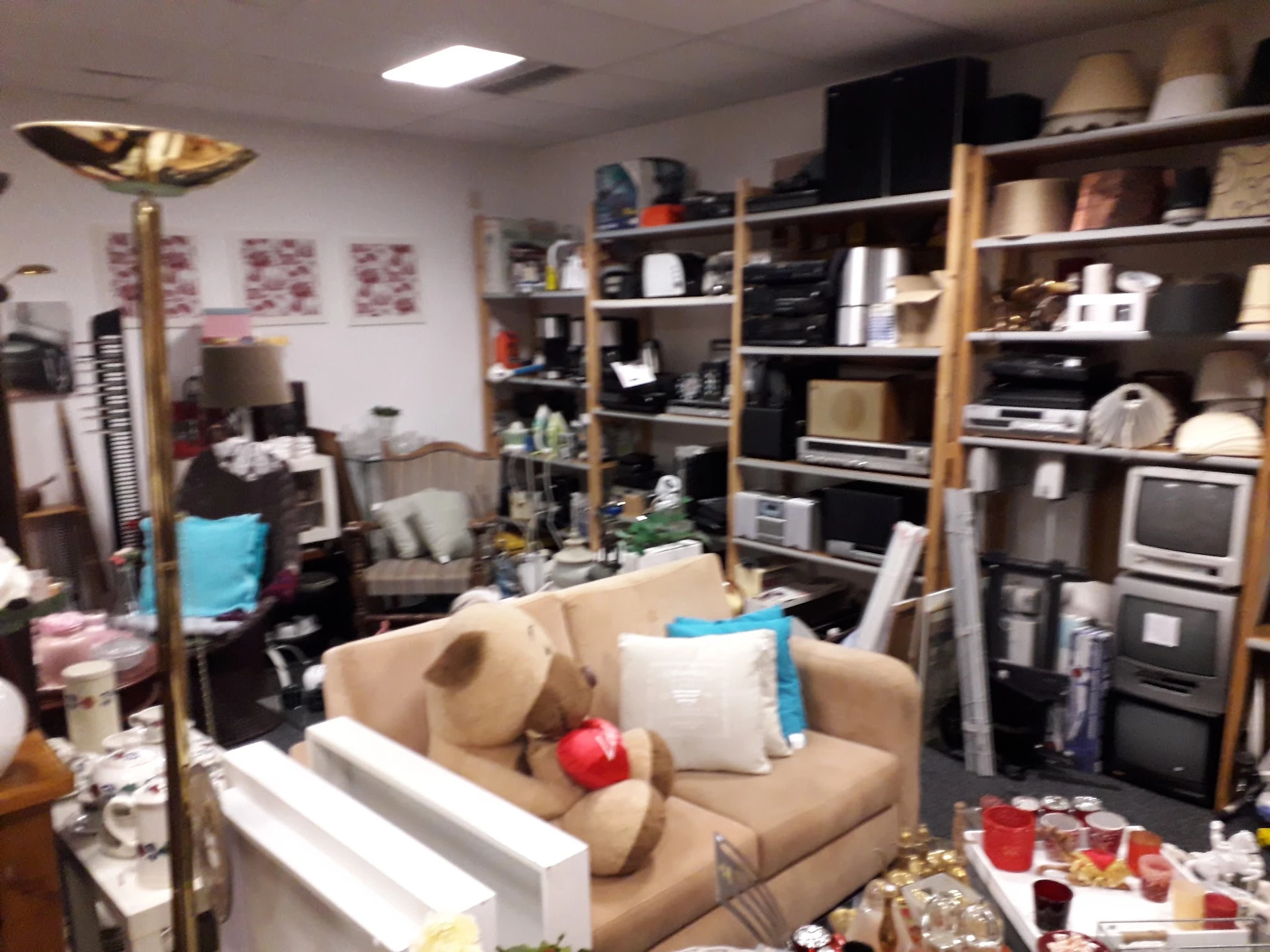Winkelvloer met meubels, stellingen vol spullen en opgestelde artikelen in een kringloopwinkel