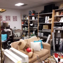 Winkelvloer met meubels, stellingen vol spullen en opgestelde artikelen in een kringloopwinkel