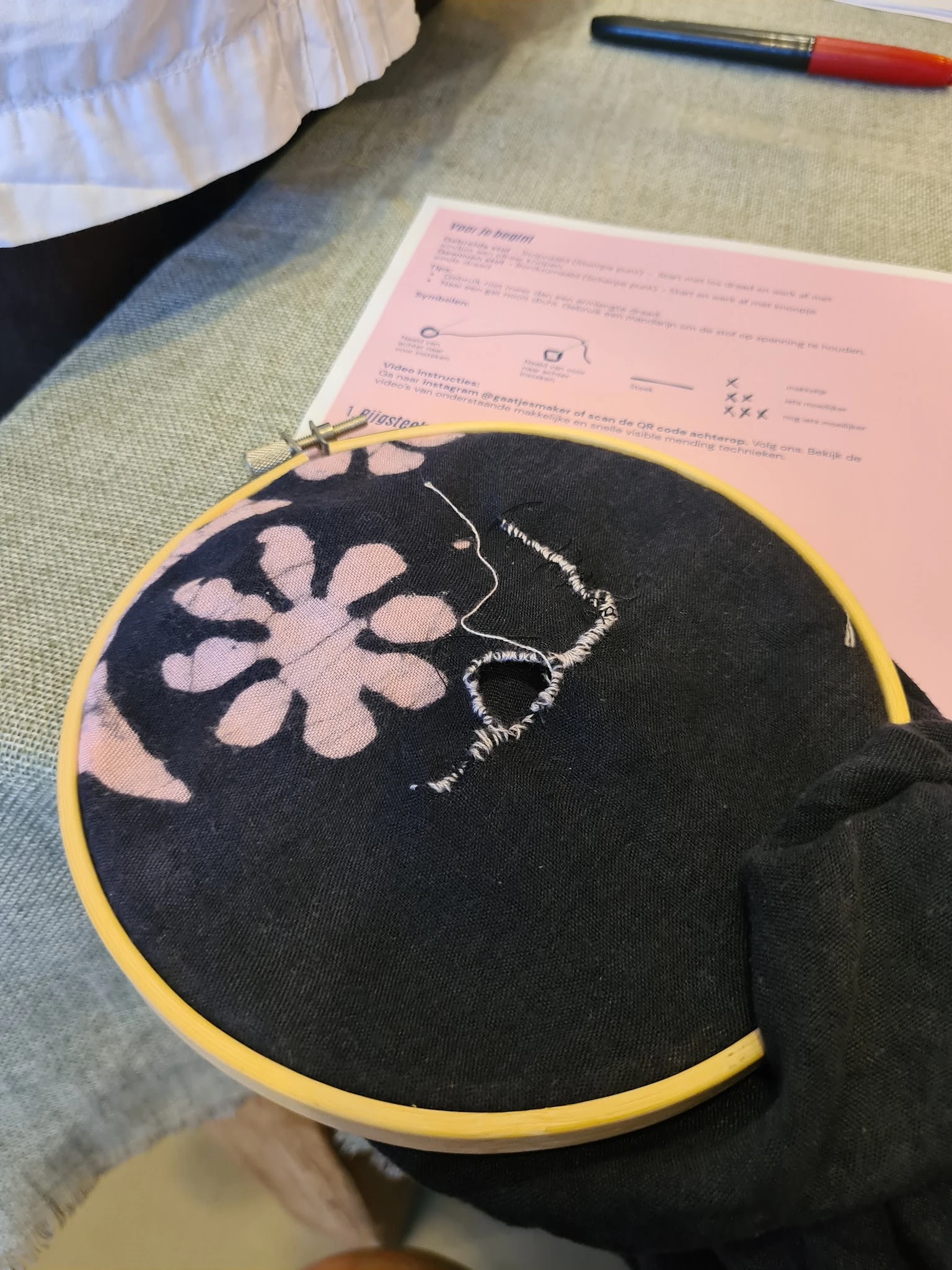 Close-up van een zwart borduurwerk met roze bloemmotief op gele ring