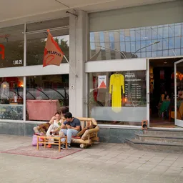 Winkelgevel met etalages en twee personen zittend op een houten bank op het terras ervoor