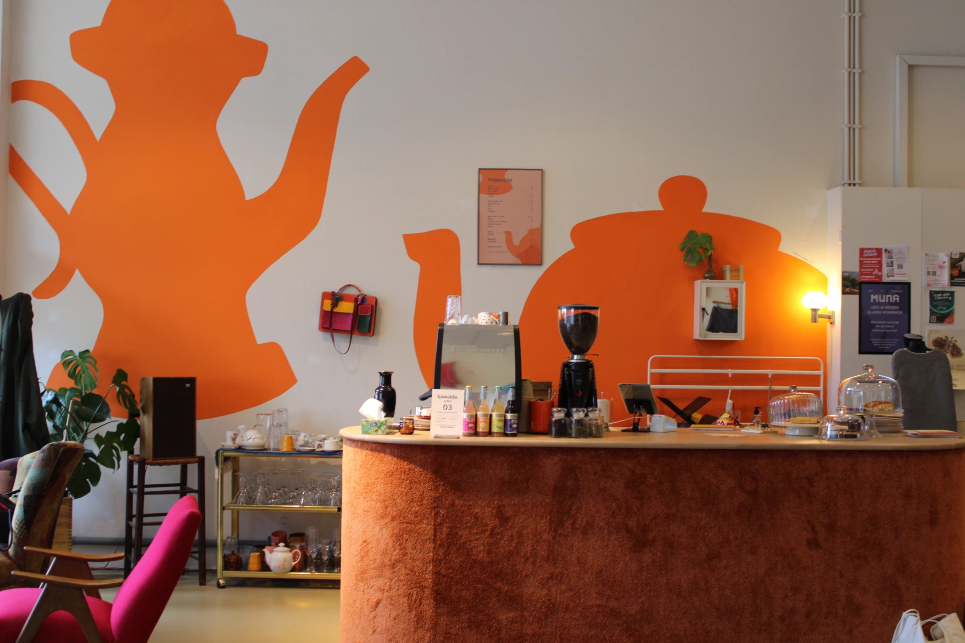 Winkelinterieur met oranje thema, toonbank met koffieapparaat en producten, grote oranje muurschilderingen