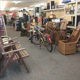 Winkelvloer met diverse tweedehands spullen: houten stoelen, fiets, rieten manden, stellingen met huishoudartikelen