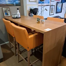 Houten eettafel met oranje barkrukken in showroom setting