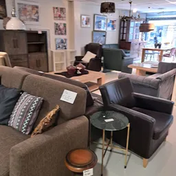 Winkelvloer met tweezitsbank, fauteuils en kleine tafels in het showroom gedeelte van de kringloopwinkel