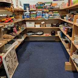 Winkelvloer met houten stellingen vol huishoudelijke spullen, dozen en diverse tweedehandsartikelen